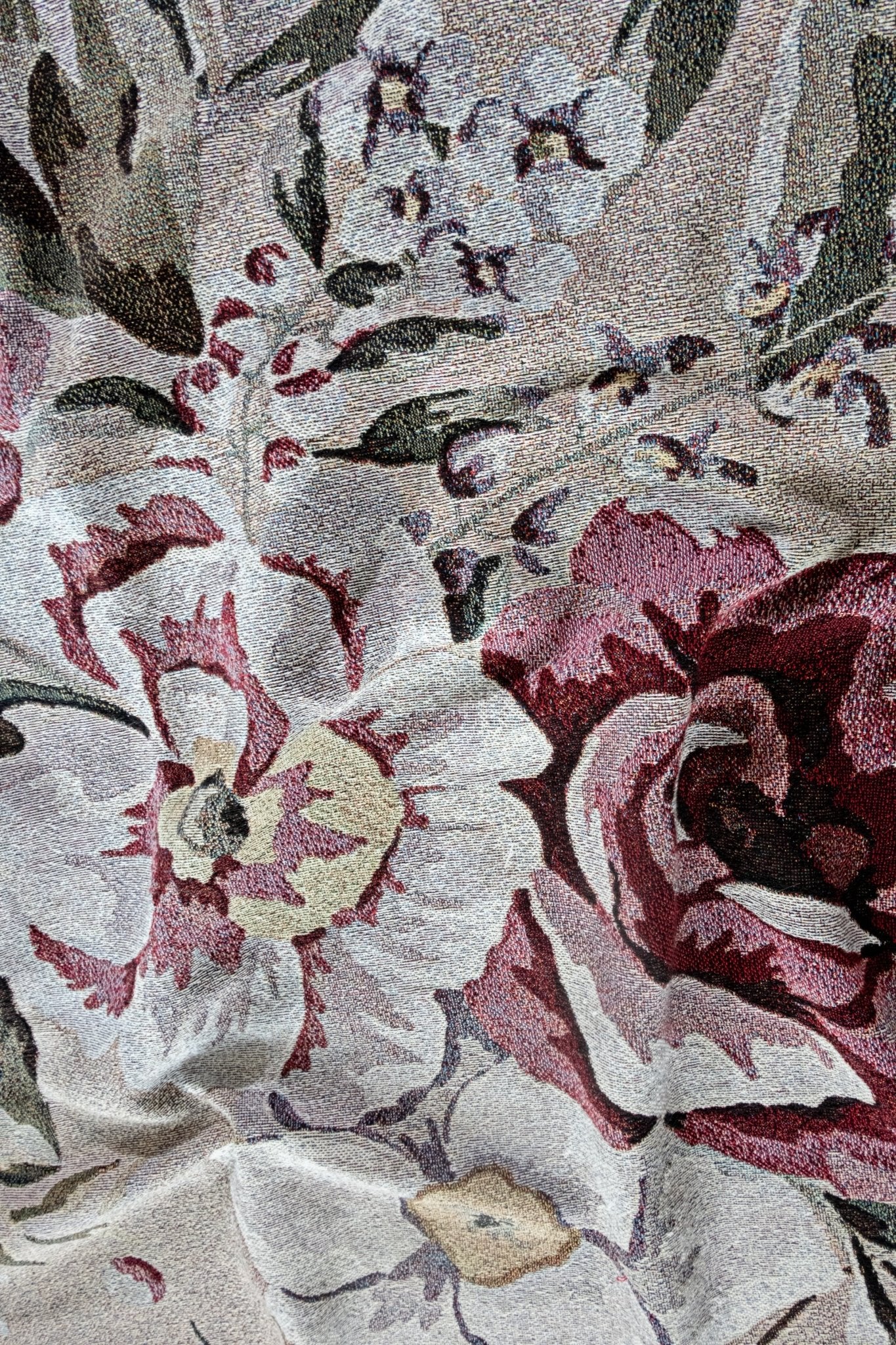 Meadow woven blanket featuring a floral pattern in shades of red, pink, and cream on a textured background.