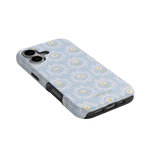 Merrigold iPhone case with a light blue floral pattern and black edges, angled view showcasing ports and buttons.