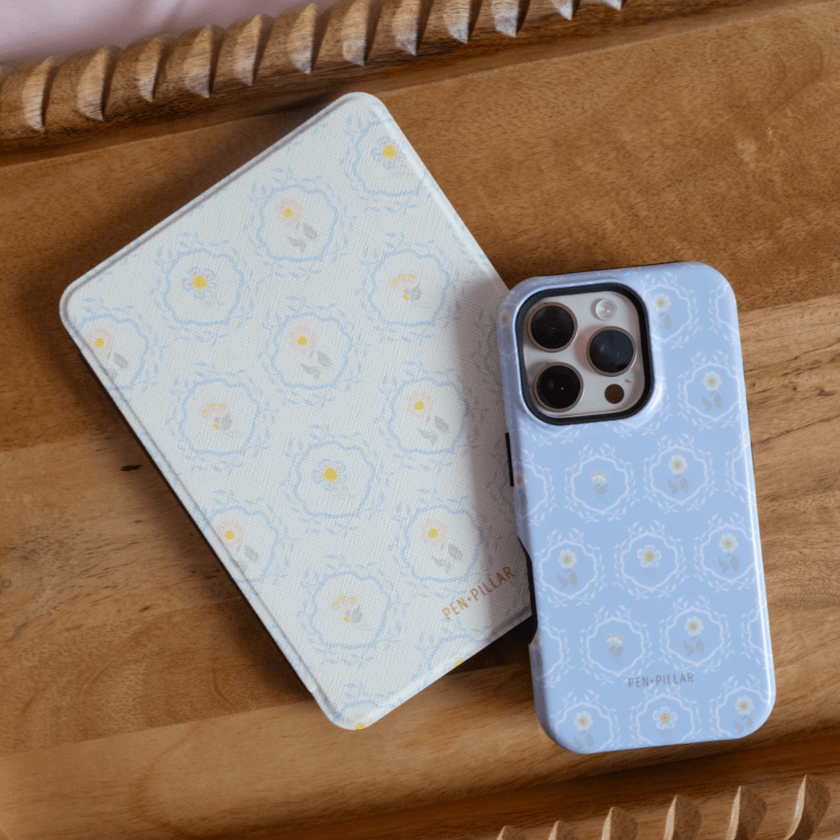 Merrigold Kindle case with floral pattern, light blue color, placed next to a matching phone case on a wooden surface.