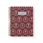 Merrigold notebook with a maroon cover featuring floral patterns and a gold spiral binding.