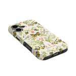 Monarch iPhone case featuring a floral and butterfly design with a black border, angled view on a green background.