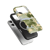 Orchard iPhone case featuring a green and beige tree design, stacked above a black and silver phone case.