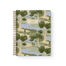 Orchard notebook featuring a landscape design with trees and water, spiral binding, and a beige label on the cover.