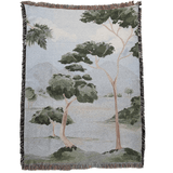 Orchard woven blanket featuring a landscape design with trees and mountains in muted green and beige tones.