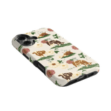 Pasture iPhone case featuring floral designs and cows on a cream background, angled to show the side and buttons.