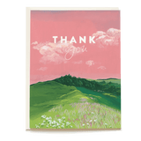 Thank you card featuring a pink sky, green hills, and white flowers in a grassy field.