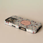 Posy personalized iPhone case featuring a floral design with a pink monogram on a light background.