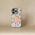 Personalized iPhone case with a floral pattern in blue, featuring a pink monogrammed initial "C" on the back.