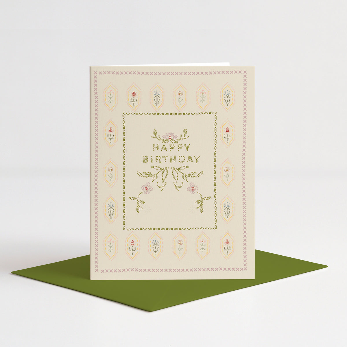Cross-Stitch Birthday Card standing on a green envelope