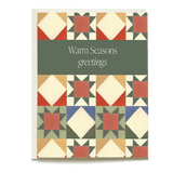 Quilt holiday card featuring a geometric pattern with warm colors and the text "Warm Seasons greetings" in the center.