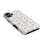 Riviera iPhone case featuring a floral pattern in blue on a cream background, angled to show side buttons.