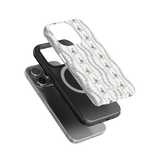 Riviera iPhone case featuring a floral design in blue on a white background, layered over two black phone cases.