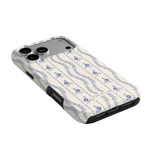 Riviera iPhone case featuring a floral pattern in blue on a cream background, angled view showing camera cutout.