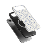 Riviera iPhone case featuring a floral design in blue on a white background, layered over a black phone case.