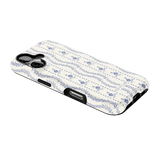 Riviera iPhone case featuring a floral pattern in blue and white on a black background, angled view showing ports.