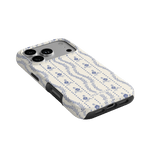 Riviera iPhone case featuring a floral pattern in blue on a cream background, angled view showing camera cutout.