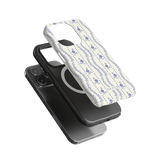 Riviera iPhone case featuring a floral design in blue on a white background, layered over a black phone.