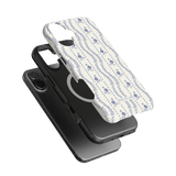 Riviera iPhone case featuring a floral pattern in blue on a white background, layered over a black phone case.