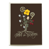 Roots sympathy card featuring a floral design with yellow and blue flowers on a dark brown background.