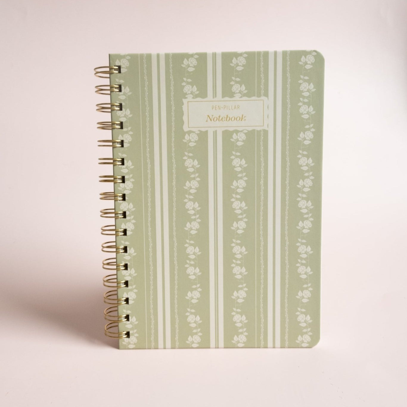 Roselle notebook with a green floral design and gold spiral binding on a light background.