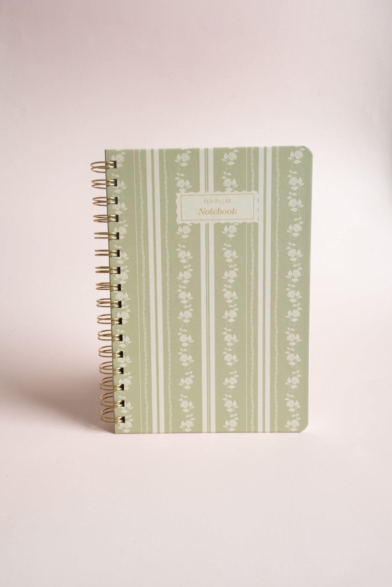 Roselle notebook with a green floral design and gold spiral binding on a light background.