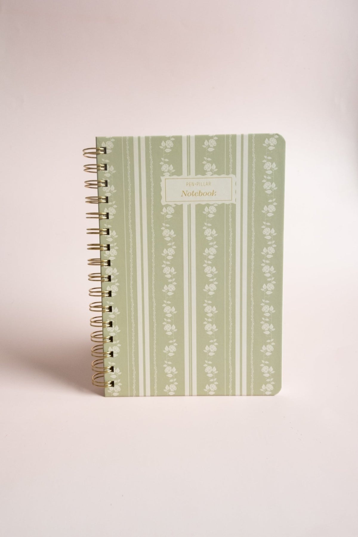 Roselle notebook with a green floral design and gold spiral binding on a light background.