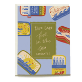 Sardines wedding card featuring colorful tin designs and the text "two less fish in the sea, congrats!" on a blue background.