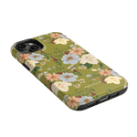 Scarlett iPhone case featuring a floral design with pastel flowers on a green background, angled to show the side.