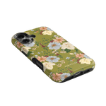 Scarlett iPhone case featuring a floral design with pastel flowers on a green background, angled view showing camera cutout.