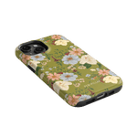 Scarlett iPhone case featuring a floral design with green background and colorful flowers, angled view showcasing edges.
