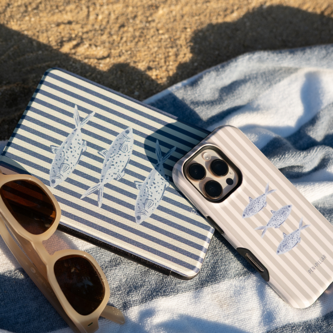 Sea Stripes iPhone case and Kindle case on a beach towel with sunglasses