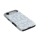 Spritz iPhone case featuring a light blue floral design with black edges, angled to show side buttons and camera cutout.