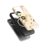 Swan Hollow iPhone case featuring floral designs in soft colors, stacked above a black phone case on a green background.