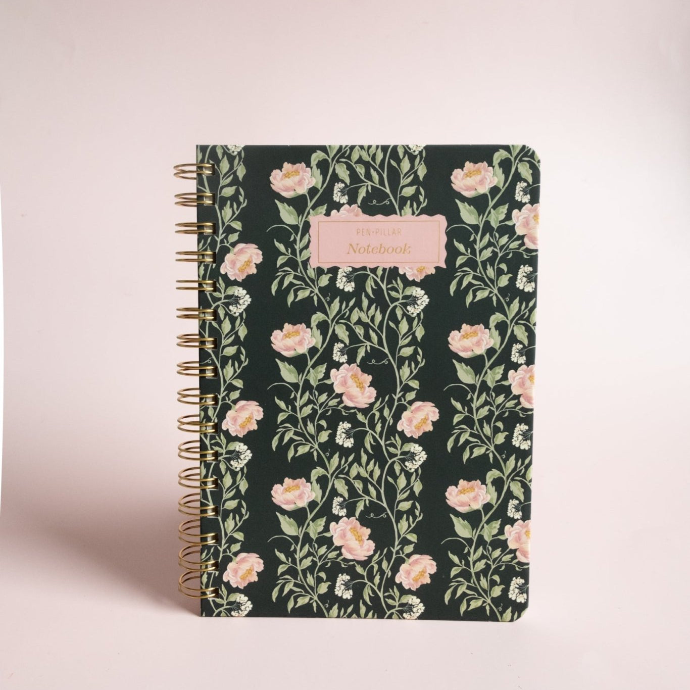 Thicket Notebook with a floral design on a dark background and a gold spiral binding.
