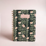 Thicket Notebook with a floral design on a dark background and a gold spiral binding.