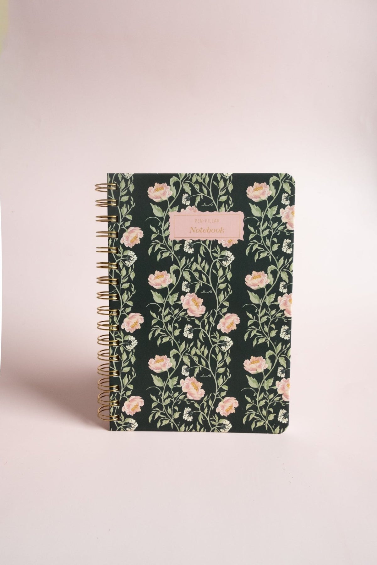 Thicket Notebook with a floral design on a dark background and a gold spiral binding.