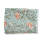 Thicket woven blanket in soft blue with floral patterns in pink and green, neatly folded.