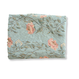 Thicket woven blanket in soft blue with floral patterns in pink and green, neatly folded.