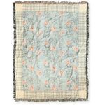 Thicket woven blanket featuring a floral pattern in soft pink and green on a light blue background with fringed edges.