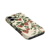 Tomato vines iPhone case featuring a cream background with red tomatoes and green leaves, angled view showing ports.
