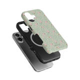 Vine+Bloom iPhone case in green with pink floral design, layered over a black case and a silver phone.