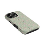 Vine+Bloom iPhone case featuring a floral pattern with pink flowers on a green background, angled view.