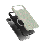 Vine+Bloom iPhone case with a green floral pattern, layered over a black phone case on a plain background.