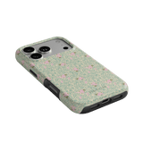 Vine+Bloom iPhone case featuring a floral design with pink flowers on a green background, angled view showing camera cutout.