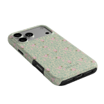 Vine+Bloom iPhone case featuring a floral pattern with pink flowers on a green background, angled view.