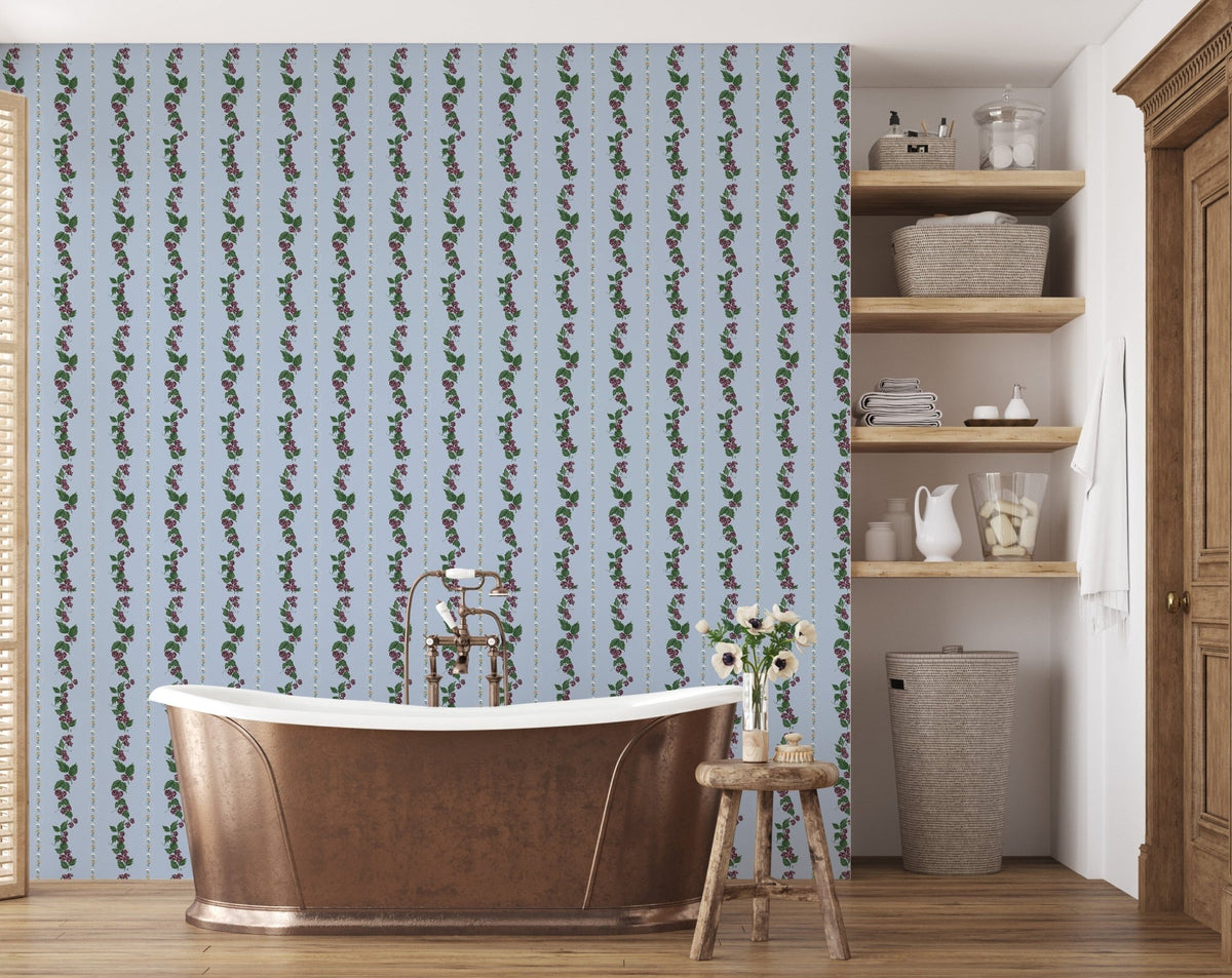 Light blue Wrenley wallpaper with vertical floral vine patterns behind a copper bathtub in a bathroom with wood floors.
