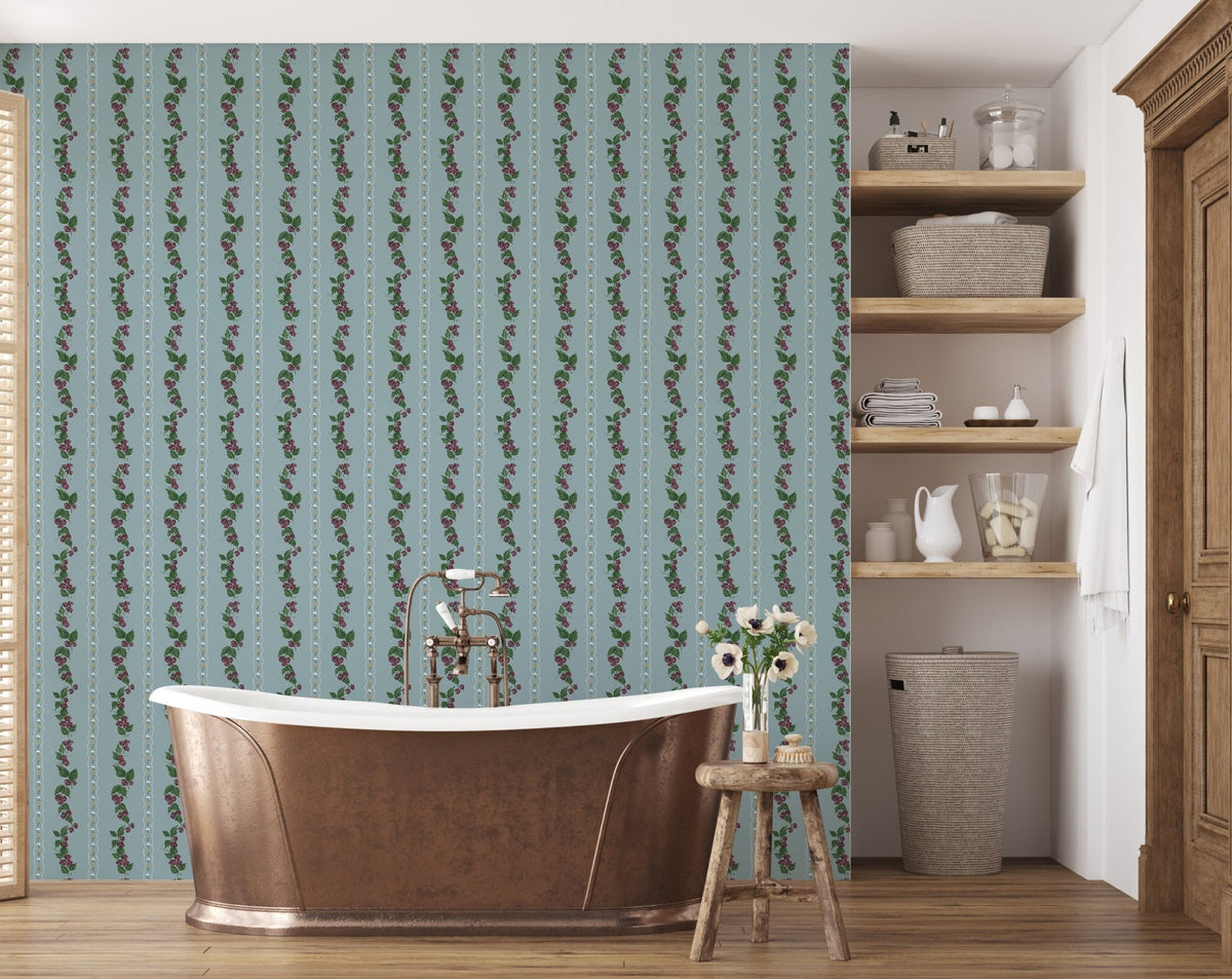 Blue wallpaper with vertical floral vine patterns behind a copper bathtub and wooden shelves.