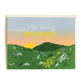 You Are My Sunshine card featuring a sunset over green hills with white and purple flowers.